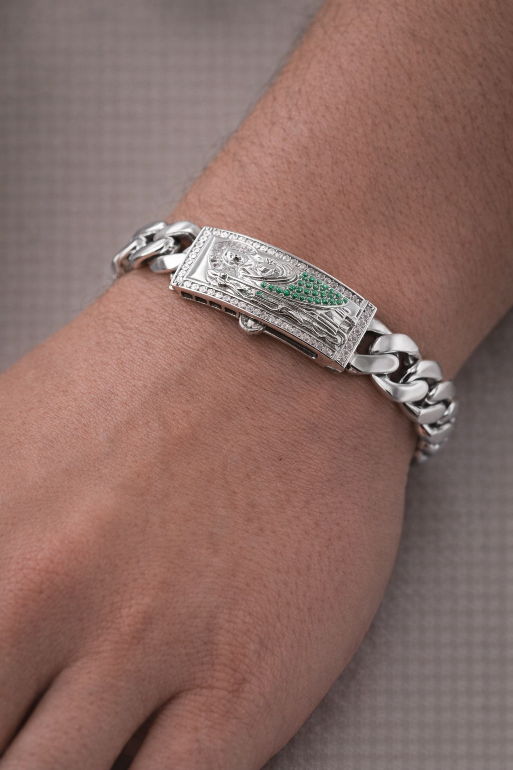 Silver bracelet with a decorative clasp worn on a wrist against a neutral background