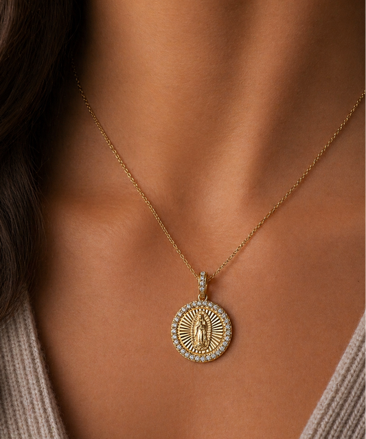 Gold necklace with a pendant on a person wearing a beige sweater.