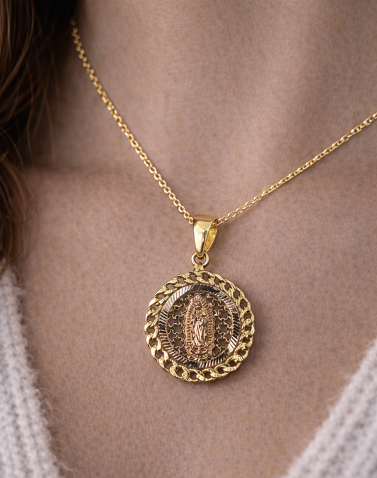 Gold necklace with a pendant on a person wearing a white sweater.