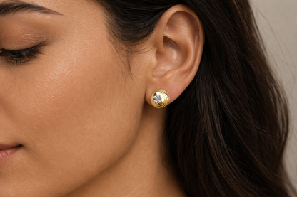 Close-up of a woman wearing gold earrings with a neutral background