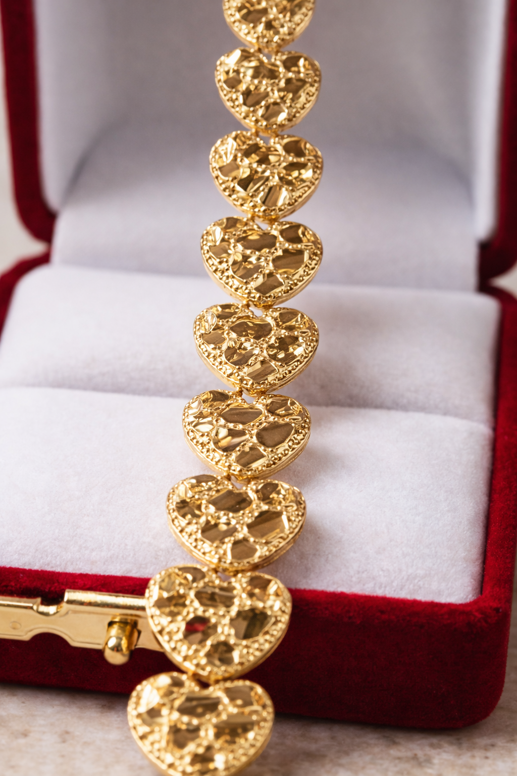 Gold bracelet with heart-shaped links in a red jewelry box