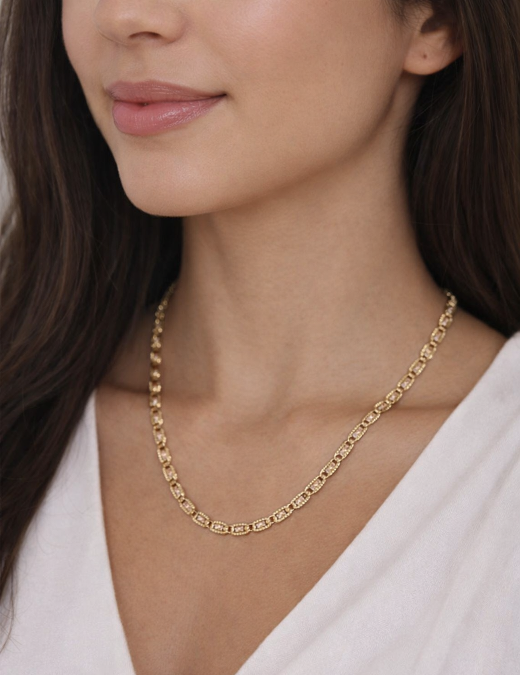 Close-up of a woman wearing a gold necklace with a plain background