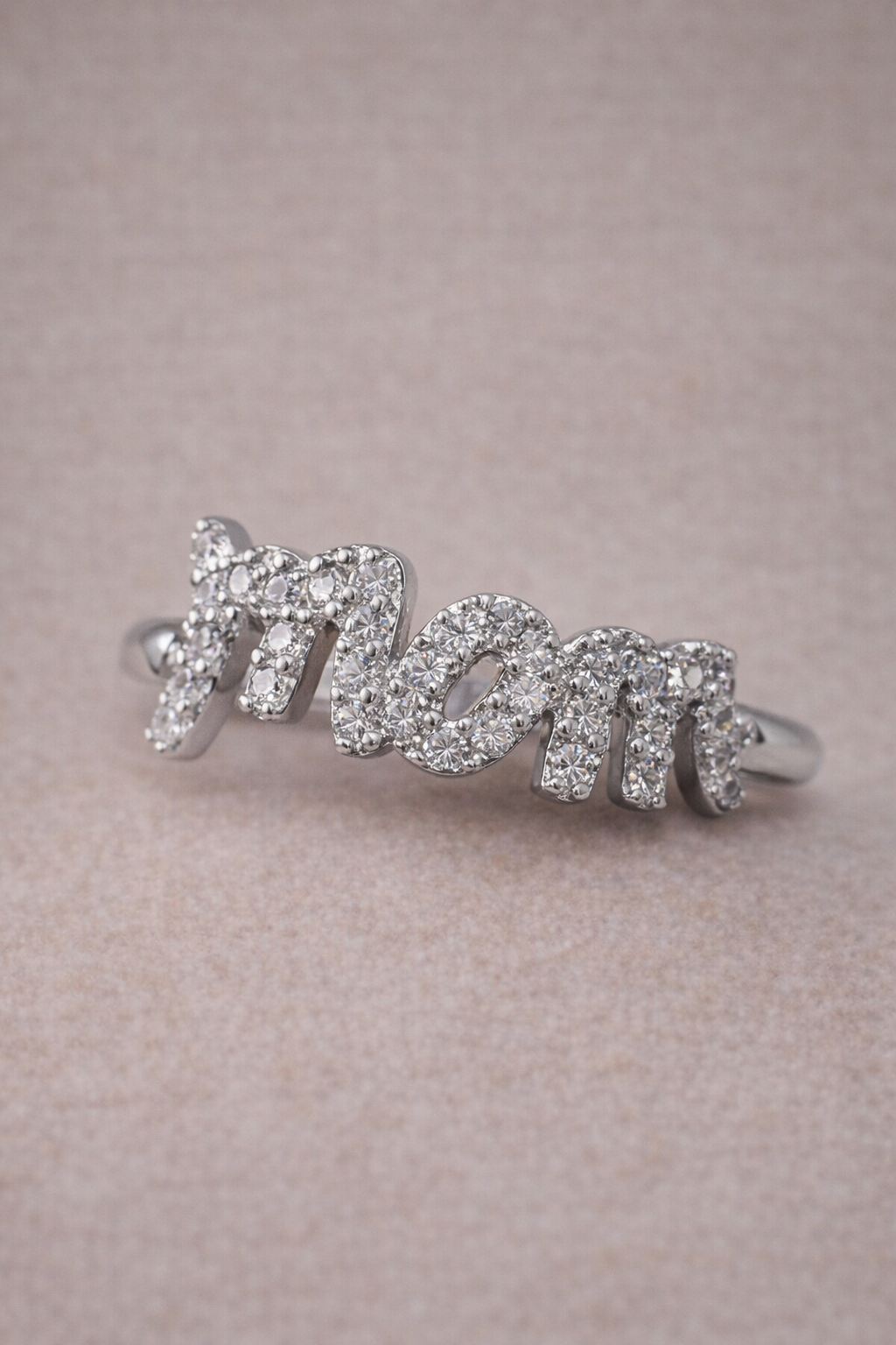 Silver ring with 'mom' text on a pink background