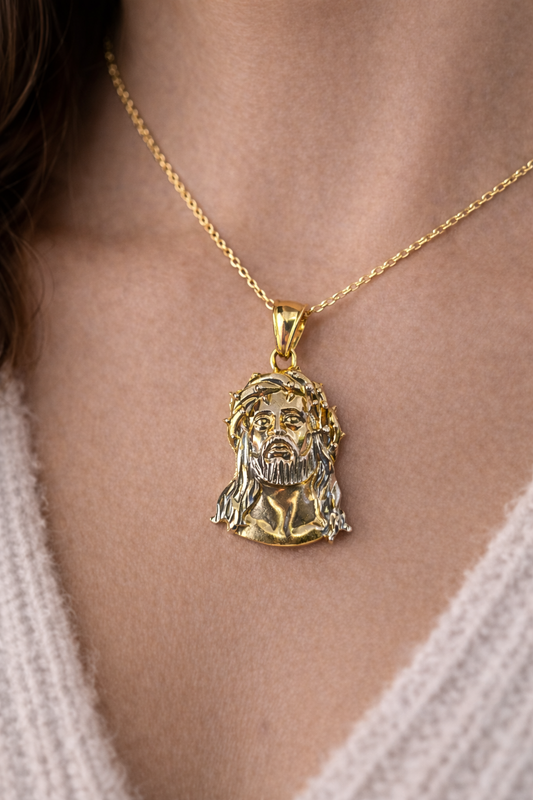 Gold necklace with a Jesus Christ pendant on a person's neck.