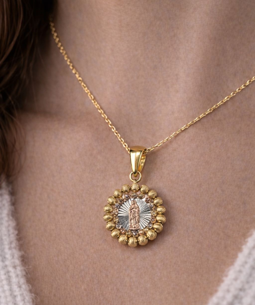 Gold necklace with a pendant featuring a religious design on a person's neck.