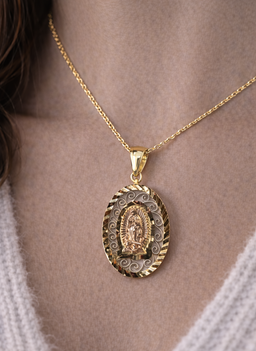 Gold pendant necklace on a person's neck with a neutral background