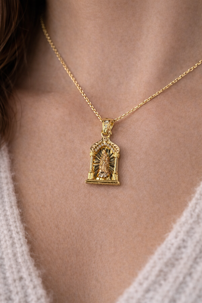 Gold necklace with a detailed pendant on a person wearing a light-colored sweater.