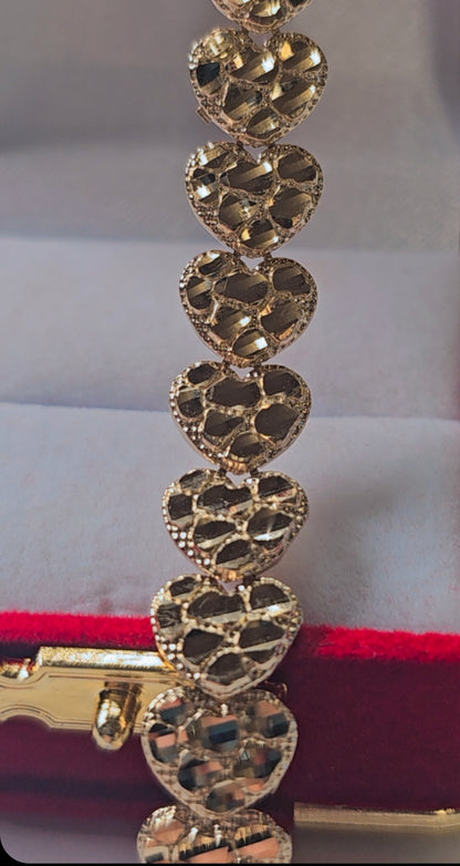 Gold bracelet with heart-shaped links on a red and white background